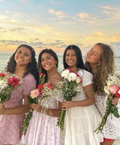 four girls standing on the beach with bouquets of flowers