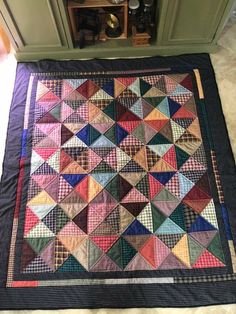 a quilt is laying on the floor next to a cabinet