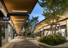 an empty shopping mall with trees and plants on the sidewalk in front of it at night