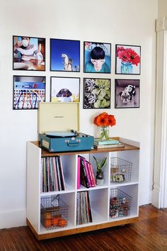 a room with pictures on the wall and a record player sitting on top of a book shelf