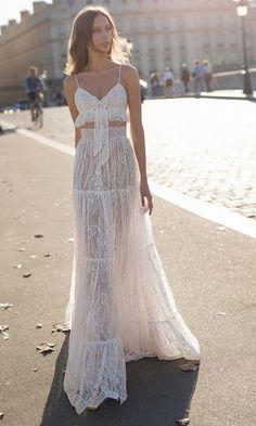 a woman is walking down the street wearing a white dress with spaghetti top and long skirt