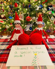 two elfs sitting in front of a christmas tree with an unwrin to find a special surprise sign