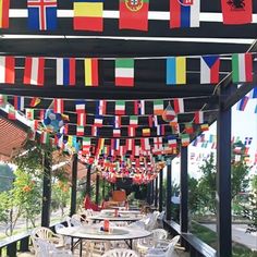 an outdoor dining area with flags hanging from the ceiling