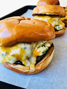 three cheeseburger sandwiches sitting on top of a baking sheet in front of the camera