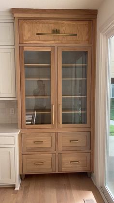 a large wooden cabinet sitting in the middle of a living room next to a window