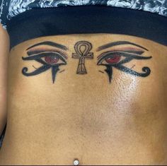 a woman's stomach with an egyptian eye tattoo on it