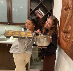 two girls are holding a tray of doughnuts