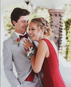 a man and woman in formal wear standing next to each other smiling at the camera