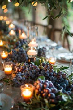 the table is set with candles, grapes and greenery for a festive look