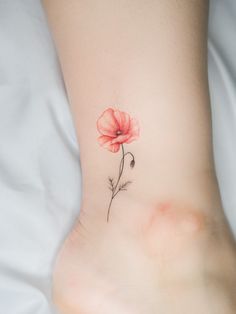 a small flower tattoo on the side of a woman's foot, with watercolors