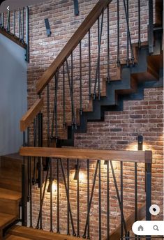 a brick wall and wooden stairs with lights on them in a room that has wood flooring