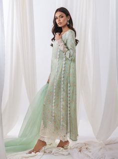 opt for elegant garden of ethereal beauty with our pastel green floral printed outfit, a masterpiece that embodies the essence of springtime elegance. The long shirt boasts with intricate cut work adorning the sleeves and hemline, The neckline is adorned with exquisite embroidery, reminiscent of blooming blossoms. Completing the ensemble with a matching organza dupatta, and pants the subtle detailing adds a touch of refinement. Shirt: Printed ShamosePants: Raw SilkDupatta: Organza Long Sleeve Lawn Suit With Resham Embroidery For Spring, Spring Floral Print Long Sleeve Lawn Suit, Green Sets With Sheer Dupatta For Spring, Spring Pista Green Set With Sheer Dupatta, Spring Wedding Lawn Suit With Intricate Embroidery, Summer Lawn Suit With Sheer Dupatta, Elegant Green Lawn Suit With Floral Embroidery, Green Long Sleeve Lawn Suit For Summer, Green Floral Embroidered Sets For Spring