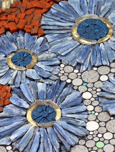 some blue and orange flowers are on a mosaic tile table top with circles around them