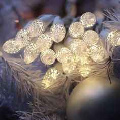 some white lights are hanging from a christmas tree ornament with snowflakes on it