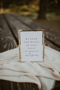 a sign sitting on top of a wooden table next to a white cloth covered blanket