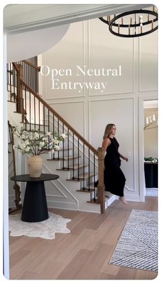 a woman in a black dress is walking up the stairs to an open neutral entryway