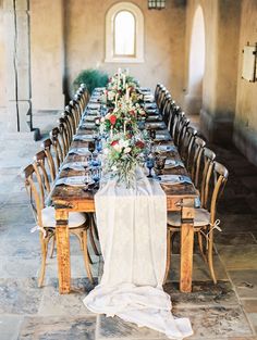 a long table set up with flowers and place settings