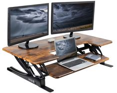 two computer monitors sitting on top of a wooden desk