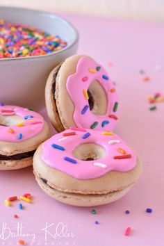 three donuts with pink frosting and sprinkles next to a bowl of cereal