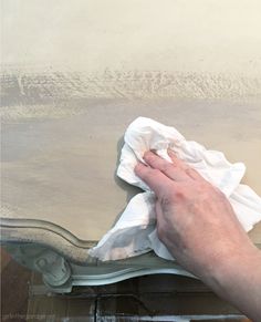 a person wiping up a piece of furniture with a cloth