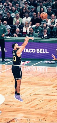 a basketball player jumping up to dunk the ball in front of an audience at a sporting event