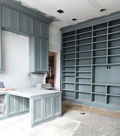 an empty room with blue bookcases and white counter tops