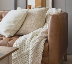 a brown leather couch with white blankets on it