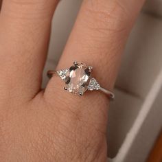 a woman's hand with a ring on it and an oval shaped morganite in the middle