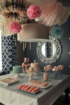 a table topped with cakes and desserts under a chandelier covered in paper flowers