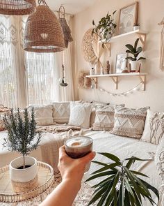 a person holding a bowl in front of a living room filled with furniture and plants