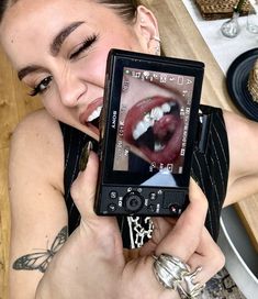 a woman holding up an open cell phone to her face with the screen showing teeth