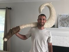 a man holding up a large white object in front of his face and smiling at the camera