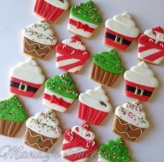 decorated christmas cupcakes are arranged on a white surface