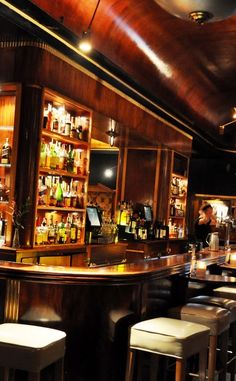 a dimly lit bar with stools in front of it