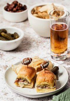 a football sandwich on a plate with pickles and crackers next to some beer