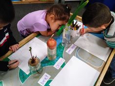 three children are sitting at a table doing arts and crafts