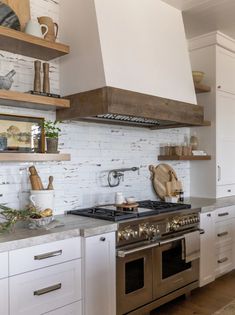 a stove top oven sitting inside of a kitchen next to white cupboards and shelves