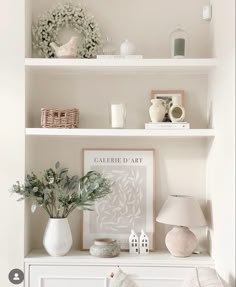 a white shelf filled with vases and other items on top of a dresser next to a lamp