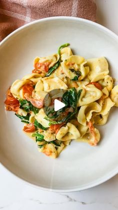 a white plate topped with pasta and spinach