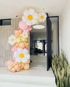 balloons are arranged in the shape of flowers on top of a white step next to a potted plant