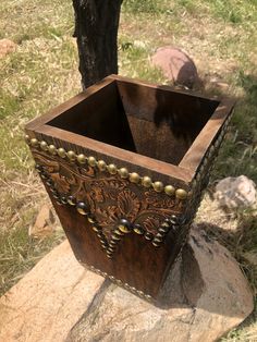 a wooden box sitting on top of a rock next to a tree