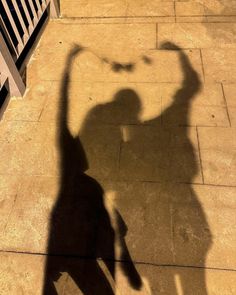 a shadow of a person holding a skateboard on the ground in front of a building