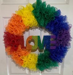 a colorful wreath with the word love spelled in large letters on it, hanging on a door