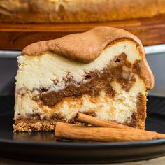 a piece of cheesecake on a plate with cinnamon sticks