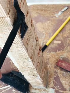 a person holding a pair of pliers in their hand while working on a piece of wood