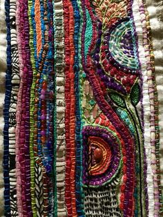 an art piece made out of different colored beads and threads on a white surface