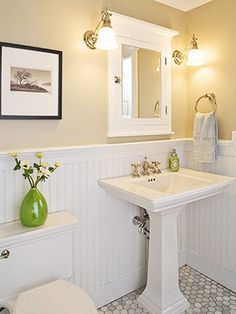 a bathroom with yellow walls, white fixtures and a green vase on the sink counter