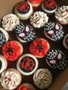 a box filled with cupcakes covered in frosting and spiderman face decorations