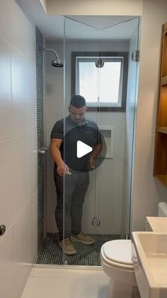 a man standing in a bathroom next to a toilet and shower with the door open