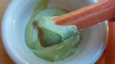 a wooden spoon in a white bowl filled with guacamole and carrots